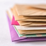 Stack of direct mail marketing envelopes in a variety of colors.
