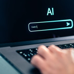 Person using a lap top and typing in a search query into an AI search.